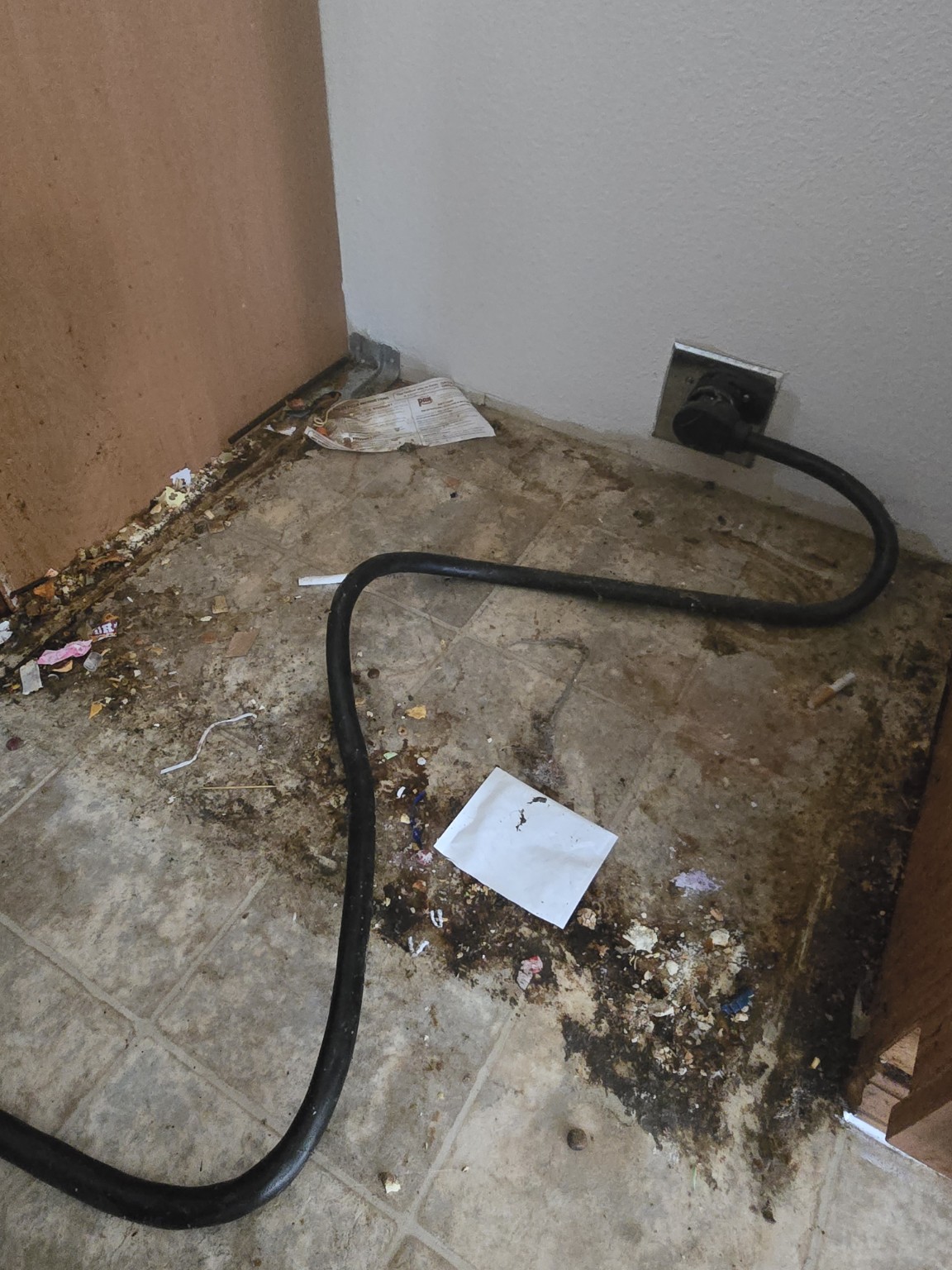 Floor behind the stove with dirt and debris before cleaning